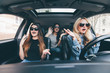 Beautiful stylish girls are sitting with open mouth while having shock during the car driving