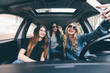 View of three beautiful young cheerful women making selfie and smiling while sitting in car together
