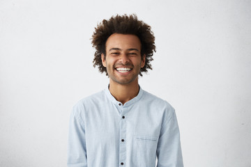 handsome unshaven young dark-skinned male laughing out loud at funny meme he found on internet, smil