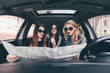 © F8  \ Suport Ukraine - view of three beautiful young cheerful women looking into the map while sitting in car