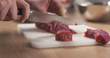young female hand cutting raw beef with a knife on plastic board, 4k photo