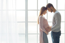 Young Couple Expecting Baby Standing Together Indoors