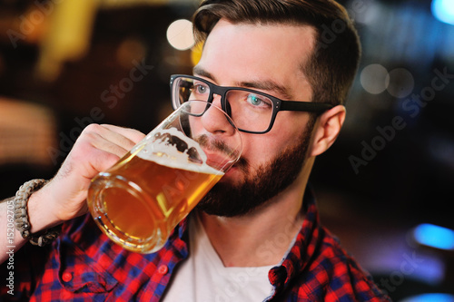 Fotomural Bearded handsome man in a plaid shirt with a glass of beer