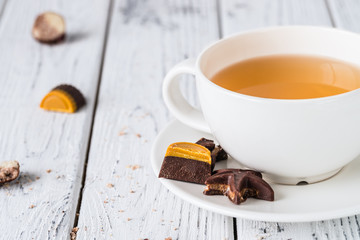 Wall Mural - Cup of tea with raw handmade chocolate candies on white wooden background. Healthy breakfast with vegan sweets