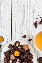 Wall Mural - Raw handmade chocolate candies, cup of tea on white wooden background. Healthy breakfast with vegan sweets. Top view with copy space