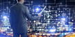 Rear view of businessman against night cityscape background and technology concept
