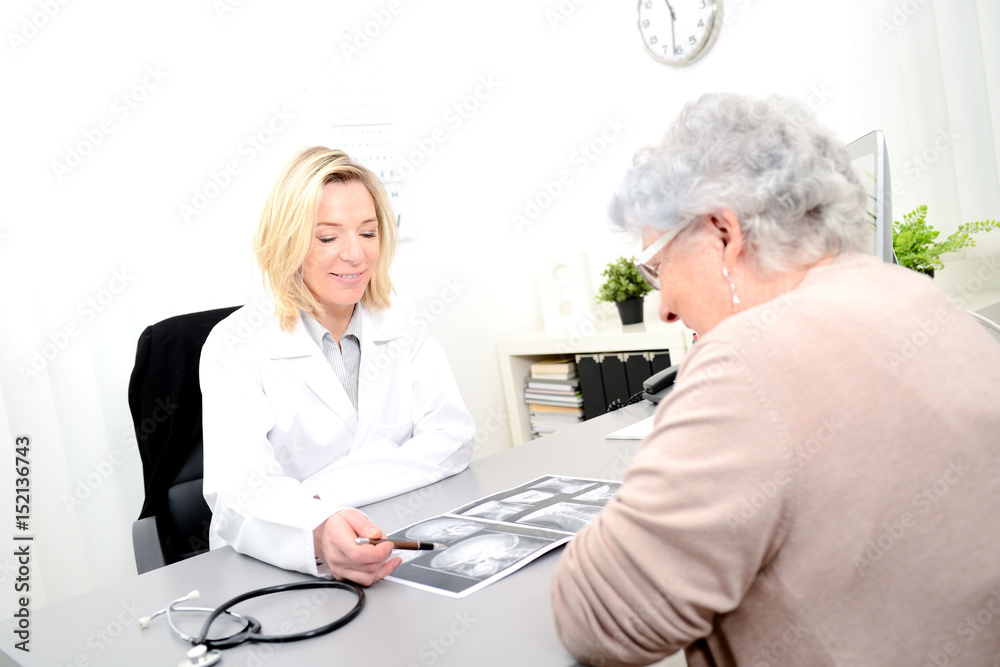 Mature female doctor in her office showing medical x-ray radiography to ...