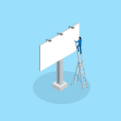 The advertising worker glues the billboard standing on the mounting ladder