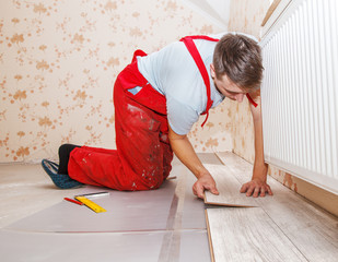 Wall Mural - young handyman installing wooden floor