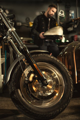 Bearded young man repairing his motorbike at the workshop