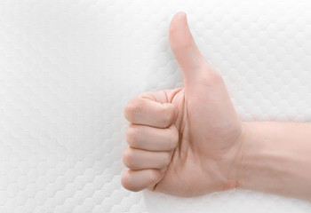 Wall Mural - Male hand showing thumb up sign and orthopedic pillow on background. Healthy posture concept