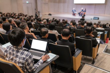 Rear view of Audience over the speakers on the stage in the conference hall or seminar meeting, business and education concept