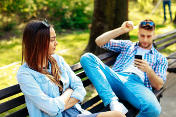 Man having fun with smartphone during a date with a beautiful woman.