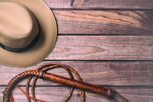 Travel And Adventure Concept. Vintage Fedora Hat And Bullwhip On Wooden Table. Top View