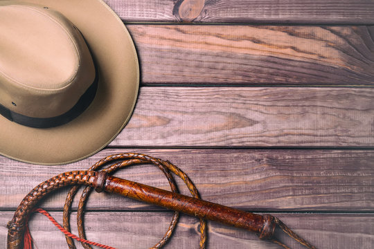 Wall Mural -  - Travel and adventure concept. Vintage fedora hat and bullwhip on wooden table. Top view