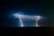 Dual bright lightning that goes into depth of black sea, with branching branches in different directions, which illuminate the southern coast of Crimea and Yalta, at night, over in the sky