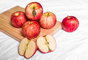 Wall Mural - Red and pink apples on a wooden board against white background