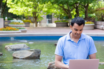 Sticker - Closeup portrait, young man in blue polo typing on laptop with background of pond and trees