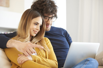 Relaxed young couple. Shot of a happy young couple relaxing at home and using a laptop.