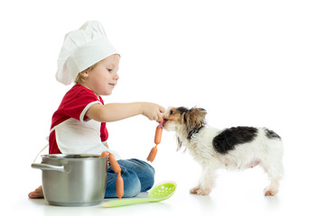 Role-playing game. Kid boy plays chef with pet. Child weared cook feeds dog.