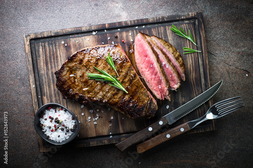 Fotografie, Obraz Grilled beef steak on wooden board. Top view.