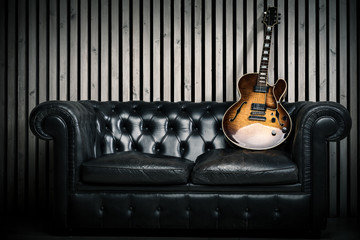 empty vintage sofa and electric guitar with modern wood wall recording studio background. Music concept with nobody 