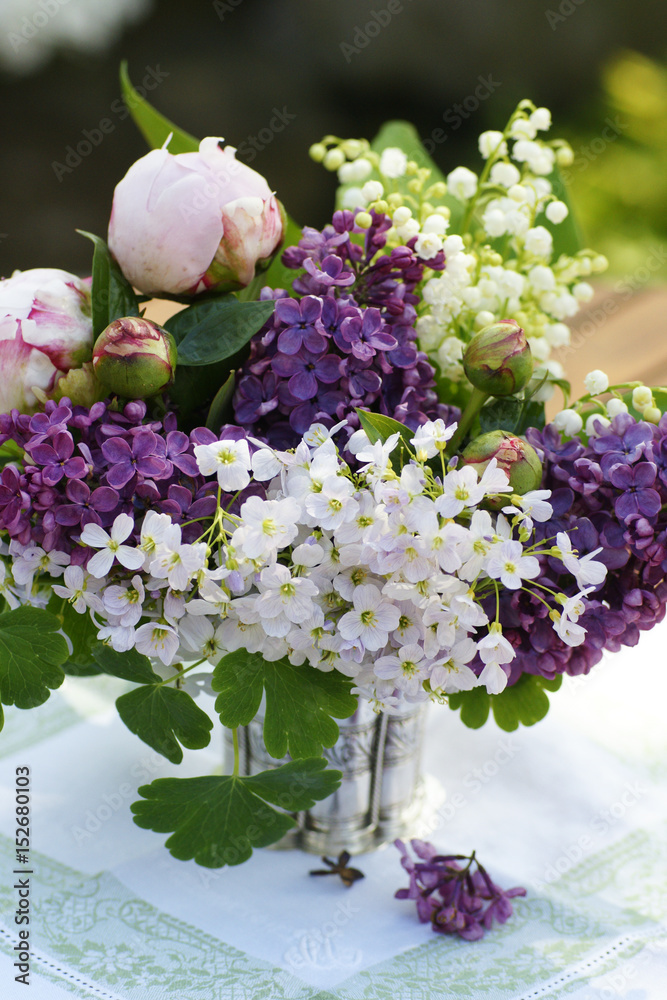 Stock-Foto „Sommerlicher Blumenstrauss auf Gartentisch mit Pfingstrosen, Maiglöckchen und Flieder“