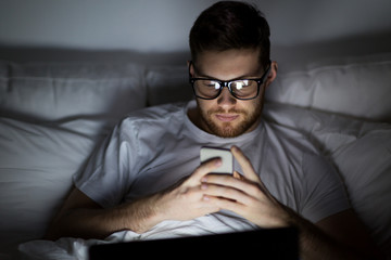 Wall Mural - man with laptop and smartphone at night in bed