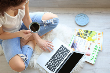 Wall Mural - Beautiful young woman using laptop at home