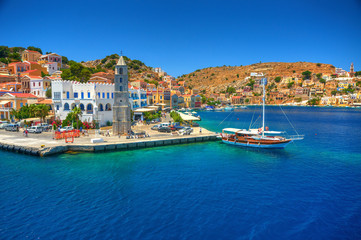 view on greek sea simy island harbor port, classical ship yachts, houses on island hills, tourists a