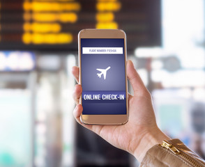 Online check in with mobile phone in airport. Woman checking in to flight with smartphone on the web. Internet self service provided by airline. Hand holding cellphone. Timetable in the background.