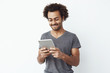 © Cookie Studio - Interested and concentrated young african man looking at tablet playing a platformer game and enjoying new levels over white bakground.