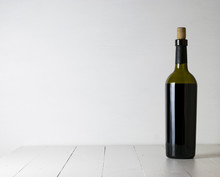 Red Wine Bottle And Corkscrew On White Wooden Table Background With Copy Space
