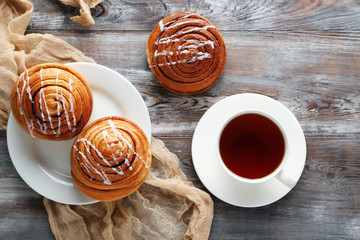 Wall Mural - Cinnamon buns with cup of tea on wooden table