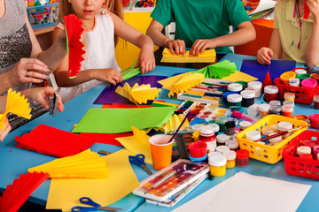 school children with scissors in kids hands cutting paper with teacher in class room. still life of 