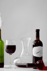 Poster - Table with wineglass and bottles of red wine on light background