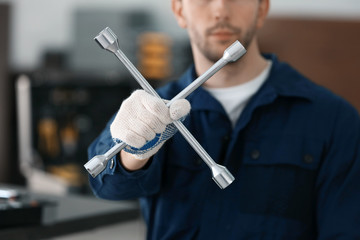 Wall Mural - Auto mechanic with wheel wrench in car repair shop