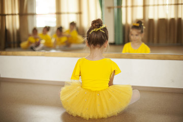 Cute little ballerina sitting in front of the mirror