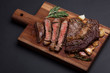 Grilled ribeye steak of marble beef closeup with spices on a wooden Board. Juicy steak medium sliced and ready to eat. With copy space. Top view