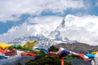 Widok na szczyt Annapurny Południowej w chmurach i flagi modlitewne.