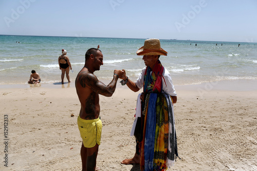 A Tourist Jokes With A Beach Seller At The Beachside Of El