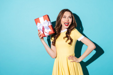 Sticker - Playful girl in dress holding gift box and looking away