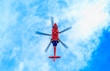 © Adam Calaitzis - Looking up underneath a blue and red helicopter against a blue sky with light clouds