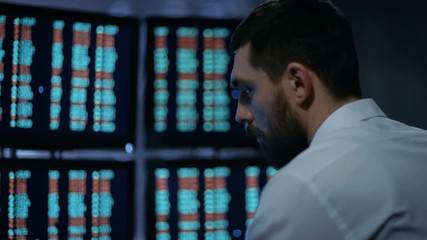 Leinwandbilder - Late at Night Trader Reads Numbers on His Multiple Displays with Stock Information on Them. In Background Big City Window View. Shot on RED EPIC-W 8K Helium Cinema Camera.