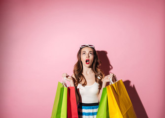 Sticker - Portrait of a cute excited girl holding colorful shopping bags