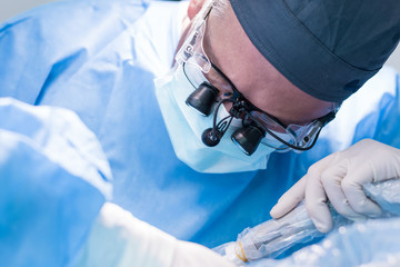 A male dentist in uniform perform dental implantation operation on a patient at dentistry office.