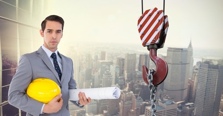 Wall Mural - Architect holding hardhat and blueprint by crane hook