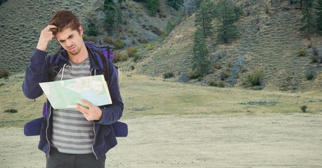 confused hiker reading map against mountain