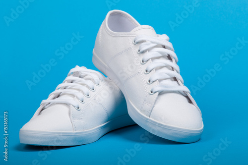 Fotografía Pair of new white sneakers on blue background