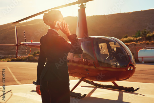 Zdjęcie XXL Biznesowa kobieta opowiada telefonem blisko helikopteru